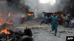A Pakistani man runs past burning vehicles at the site of a bomb explosion in the busy Kissa Khwani market in Peshawar on September 29.