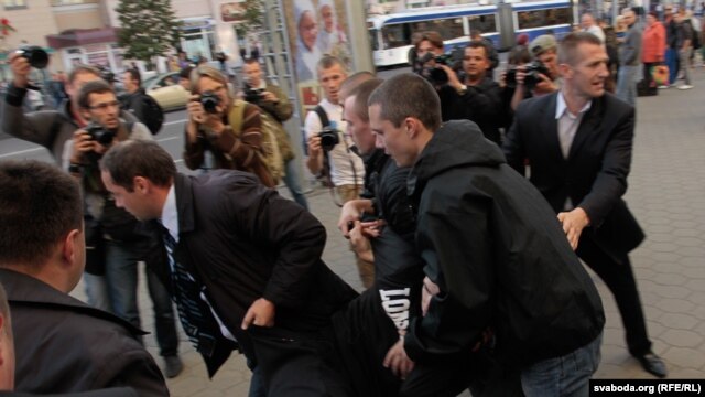 A protester is bundled away by unknown men in Minsk