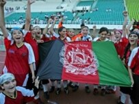 Afghan women's soccer team flies the national flag after beating Pakistan's Baluchistan team on August 22 (AFP)