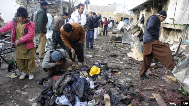 Local residents look at clothes left in a pile at the site of overnight twin suicide bombings in Quetta on January 10.