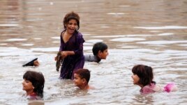 Pakistani children play in floodwaters following heavy rain in Aza Kheil, some 40 kilometers from Peshawar.