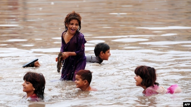 Pakistani children play in floodwaters following heavy rain in Aza Kheil, some 40 kilometers from Peshawar.