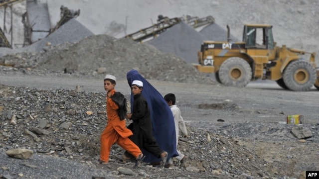 An Afghan woman and her children walk near an open-cast mine in the Turkham Nangarhar region of Afghanistan bordering Pakistan. Manufacturing, mining, and Afghanistan's agricultural sectors would be the most likely areas of investment. 