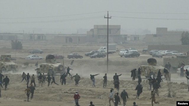 Protesters throw stones at Iraqi security forces during an antigovernment demonstration in Falluja on January 25.