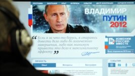 A man looks at a computer monitor displaying the main page of Prime Minister Vladimir Putin's election campaign website.