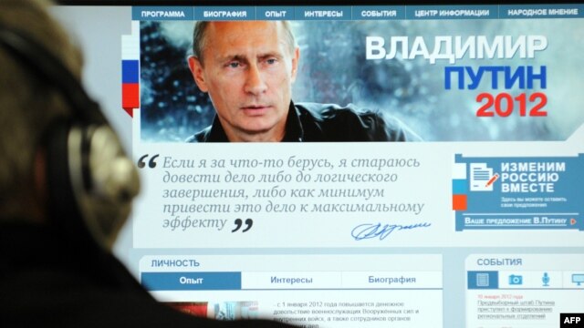 A man looks at a computer monitor displaying the main page of Prime Minister Vladimir Putin's election campaign website.