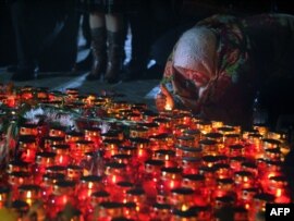 A woman lights a candle at the monument to victims of the Holodomor, Ukraine's great famine in 1932-33, in Kyiv on November 24