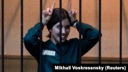 Jailed Pussy Riot member Nadezhda Tolokonnikova gestures as she looks out from a holding cell during a court hearing in April.