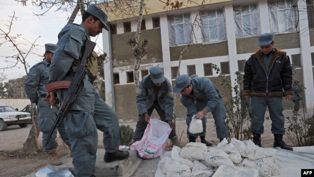 Afghan policemen stand next to packages containing opium during a police presentation in Herat in December.