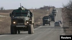 Pro-Russian fighters ride in the back of a truck towing a mobile artillery cannon as they leave the front line and head toward Donetsk on February 23.