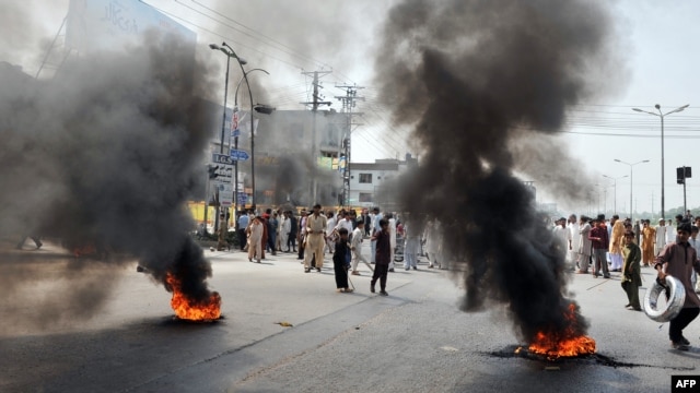 Demonstrators gather behind burning tires as they block a main highway during a protest in Rawalpindi on September 21.