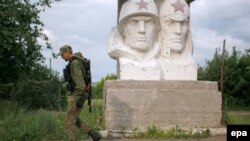 Горловка маңындағы Зайцево селосында совет жауынгерлері ескерткіші қасынан өтіп бара жатқан қарулы сепаратист. Донецк облысы, Украина. 26 мамыр 2016 жыл.