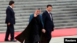 Afghan President Hamid Karzai (center) and Chinese President Xi Jinping (right) respond to children waving the national flags of their two countries at a welcoming ceremony outside the Great Hall of the People in Beijing on September 27.