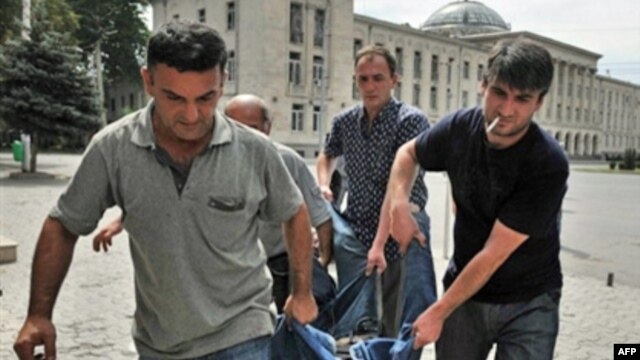 Men carry the body of a man killed by a shell in the town of Gori on August 12