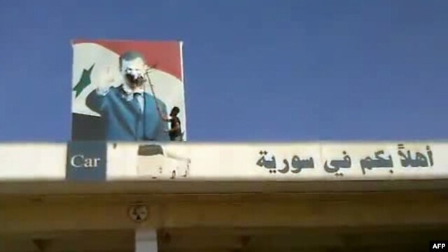 Purportedly a Syrian rebel defacing an image of President Assad at Bab al-Hawa border crossing between Syria and Turkey, on July 19