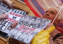 A woman holds a placard that shows victims of hazing and reads \