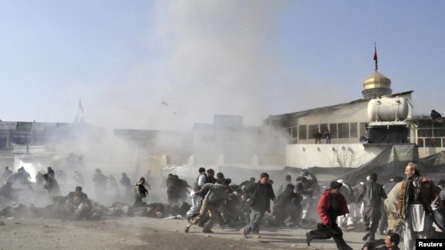 People react seconds after a suicide blast targeting a Shi'ite Muslim gathering in Kabul on December 6. Fifty-five people were killed and over 160 injured.