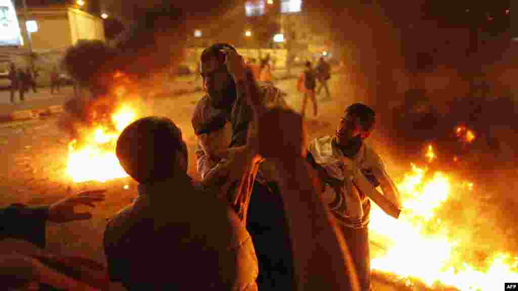 Members of the Muslim Brothood and supporters of Egyptian President Muhammad Morsi carry an injured comrade during clashes with anti-Morsi protesters on the road leading to the Egyptian presidential palace in Cairo. (AFP/Mahmoud Khaled)