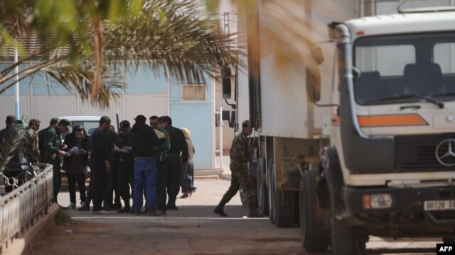 Algerian security and forensic officers monitor as bodybags of victims that were killed during the hostage crisis at a desert gas plant in Algeria's deep south are unloaded from refrigerated trucks in In Amenas on January 21.