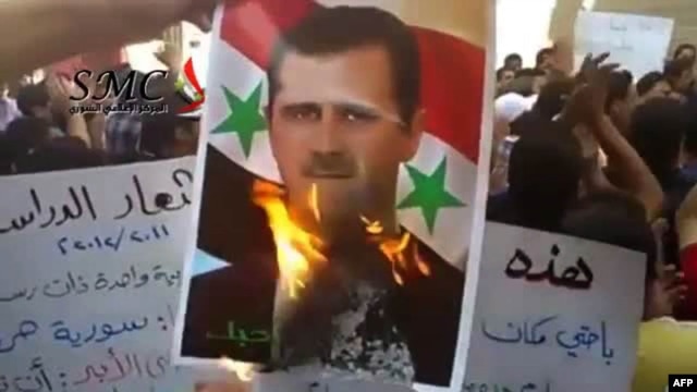 An image grab from footage uploaded on YouTube shows a protester burning a picture of Syrian President Bashar al-Assad during an antiregime demonstration in Damascus in September.