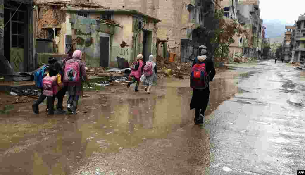 Syrian girls walk in the rain as they return from school in the southwestern city of Daraa. The bombardment of the city has ended amid a shaky cease-fire and Syrian children in the city have been able to return to school. (AFP/Fadi Dirani)
