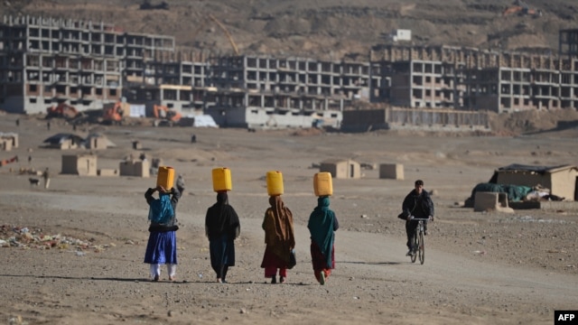 Kuchi women carry water on their heads on the outskirts of Kabul in late November.