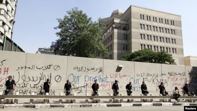 Egyptian security personnel stand guard near a wall with graffiti at the U.S. Embassy in Cairo, where protesters gathered to condemn a film being produced in the United States that insulted the Prophet Mohammad.