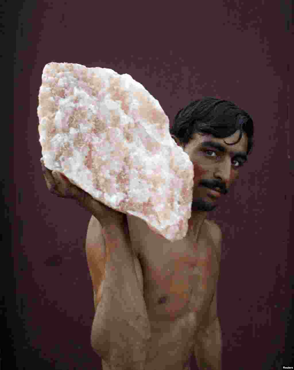 A laborer, carrying rock salt for loading onto a railway carriage, stops to pose for a photo on a train-station platform in Khewra. 