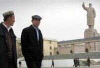 Uyghur men walking past a statue of Mao Zedong in Kashgar (file photo) (AFP)