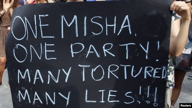 Students hold up a poster with a reference to President Mikheil Saakashvili and a recent torture scandal.