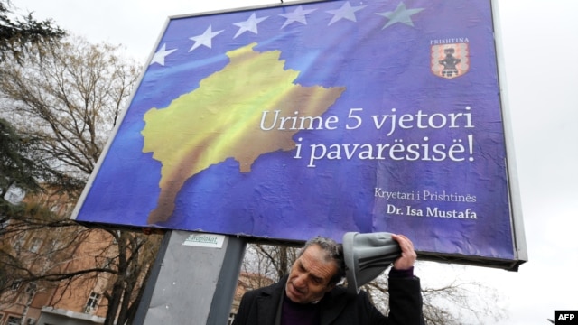 Priština, prolaznik pored bilborda na kojem piše Srećna peta godišnjica nezavisnosti, februar 2013.
