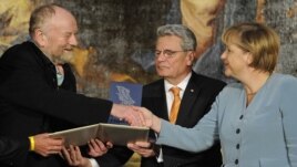 Danish cartoonist Kurt Westergaard (left) is congratulated on his prize by German Chancellor Angela Merkel (right) at the M100 Media Prize ceremony in Potsdam on September 8