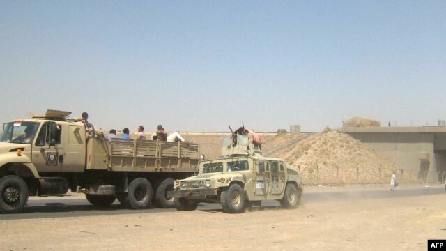 Иракские военнослужащие в гражданской одежде покидают город Киркук 11 июня 2014 года
