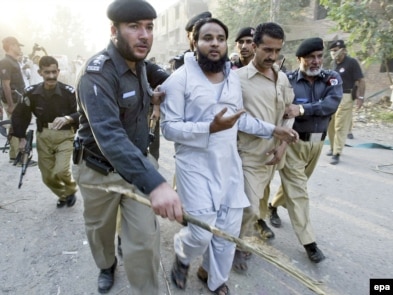 Pakistani police arrest a suspect after a suicide car-bomb attack outside a police station in Kohat on October 15.