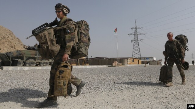 French soldiers from the 92nd Infantry Battalion leave with their backpacks as the Afghan national flag flies after an official handover ceremony of the Forward Operating Base Tora Surobi on July 31.
