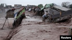 Men collect try to collect their belongings from a makeshift shop on the outskirts of Peshawar after it was hit by flooding following torrential rain in Khyber Pakhtunkhwa Province on April 3.