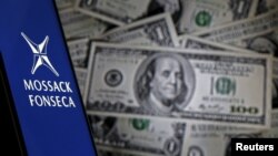 Смартфон с логотипом панамской офшорной компании Mossack Fonseca на фоне банкнот номиналом один доллар.