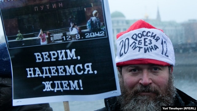 One of the tens of thousands of Moscow protesters holds a sign saying: "We believe, we hope, we wait!"  His hat says: "Russian without Putin" 2012. 