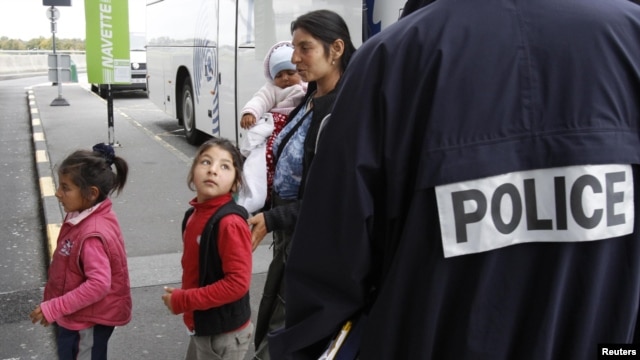 A Roma family walks past a police officer as they arrive at the Lille-Lesquin airport, near Lille in northern France, for their flight to Romania on September 16.