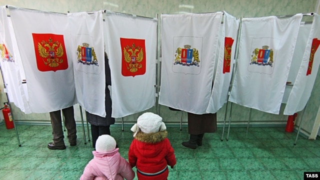 Children wait as their parents vote in ballot booths at a polling station in Ivanovo.