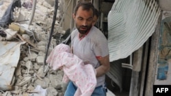 A Syrian man carries a dead baby retrieved from under the rubble of a building following an air strike on the Al-Muasalat area of Aleppo on September 23, 2016. 