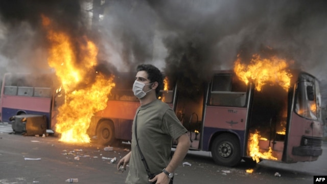 A supporter of defeated Iranian presidential candidate Mir Hossein Musavi stands in front of a burning bus during riots in Tehran.