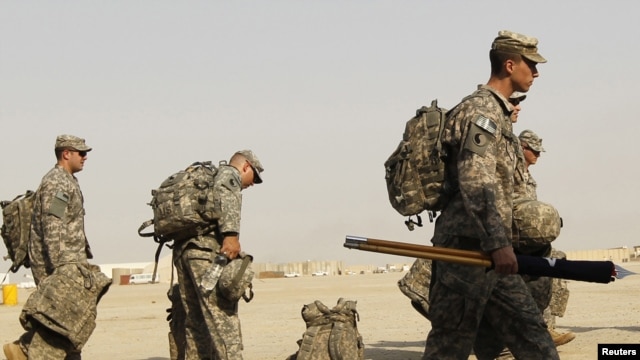 U.S. soldiers carry their luggage as they prepare to pull out of Iraq at Tallil Air Base near Nassiriya