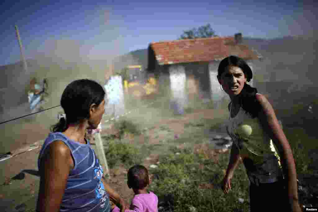 Bulgarian Roma women react as a bulldozer tears down their home in a Roma suburb in the town of Maglizh, some 260 kilometers east of Sofia on September 25. The municipal authorites had ordered the demolishment of some 30 illegally built houses in the area. (REUTERS/Stoyan Nenov)
