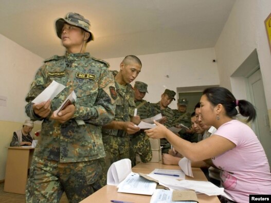 Soldiers receive ballot papers before casting their votes in a referendum at a polling station in Osh