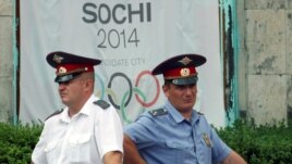 Russian policemen stand in front of a banner promoting Sochi during bidding to host the 2014 Winter Olympics.