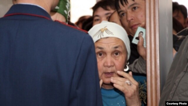 Полицей айыпталушылардың туыстарымен сөйлесіп тұр. Ақтау, 27 наурыз 2012 жыл. (Фото Lada.kz сайтынан алынды)