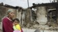 An ethnic Uzbek woman on June 16 carries her child past homes destroyed during the clashes in her village, Kyr-Aryk in the Osh region.