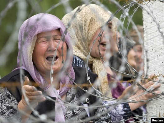 Ethnic Uzbek refugees who have fled from clashes in Osh cry as they gather on the border while waiting for permission to escape to Uzbekistan on June 15, 2010.