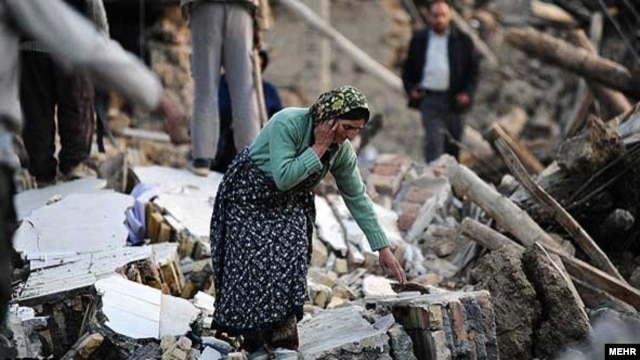A woman walks among destroyed houses in the Iranian city of Varzaqan in Iran's northwestern province of East Azerbaijan on August 12.